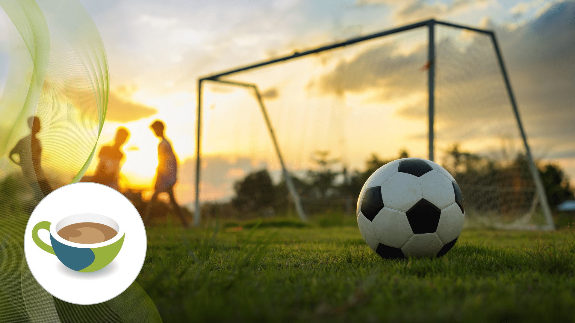 A soccer ball resting on a grassy field in front of a goal net at sunset, with silhouettes of players in the background.