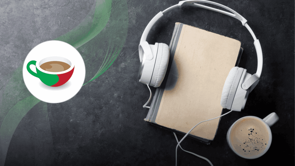 A book with white over-ear headphones resting on top, next to a cup of coffee with foam on a dark textured surface