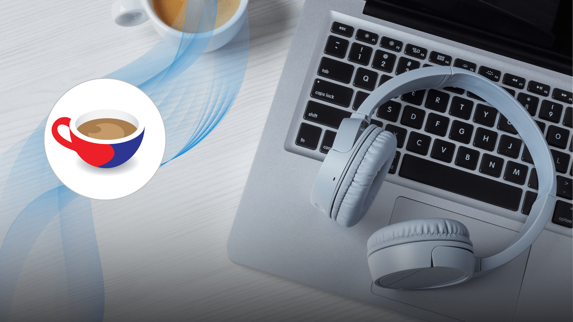 Close-up of a laptop keyboard with a pair of white over-ear headphones resting on it, alongside a cup of espresso on a white wooden desk.