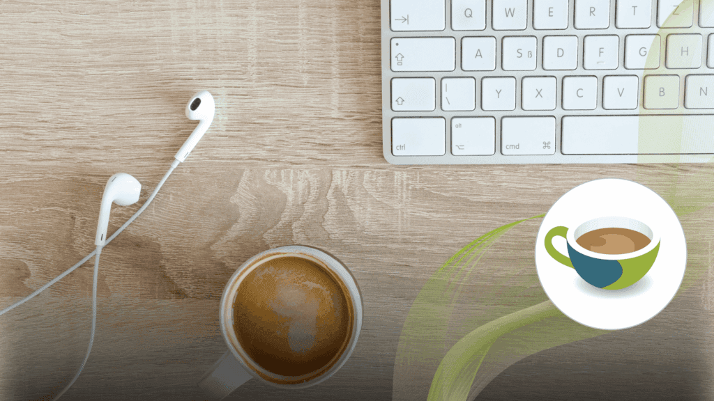 A wooden desk with a cup of coffee, white earphones, and part of a computer keyboard.