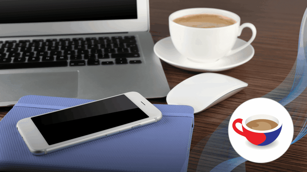 A laptop, notebook, smartphone and computer mouse on a wooden desk beside a cup of coffee.