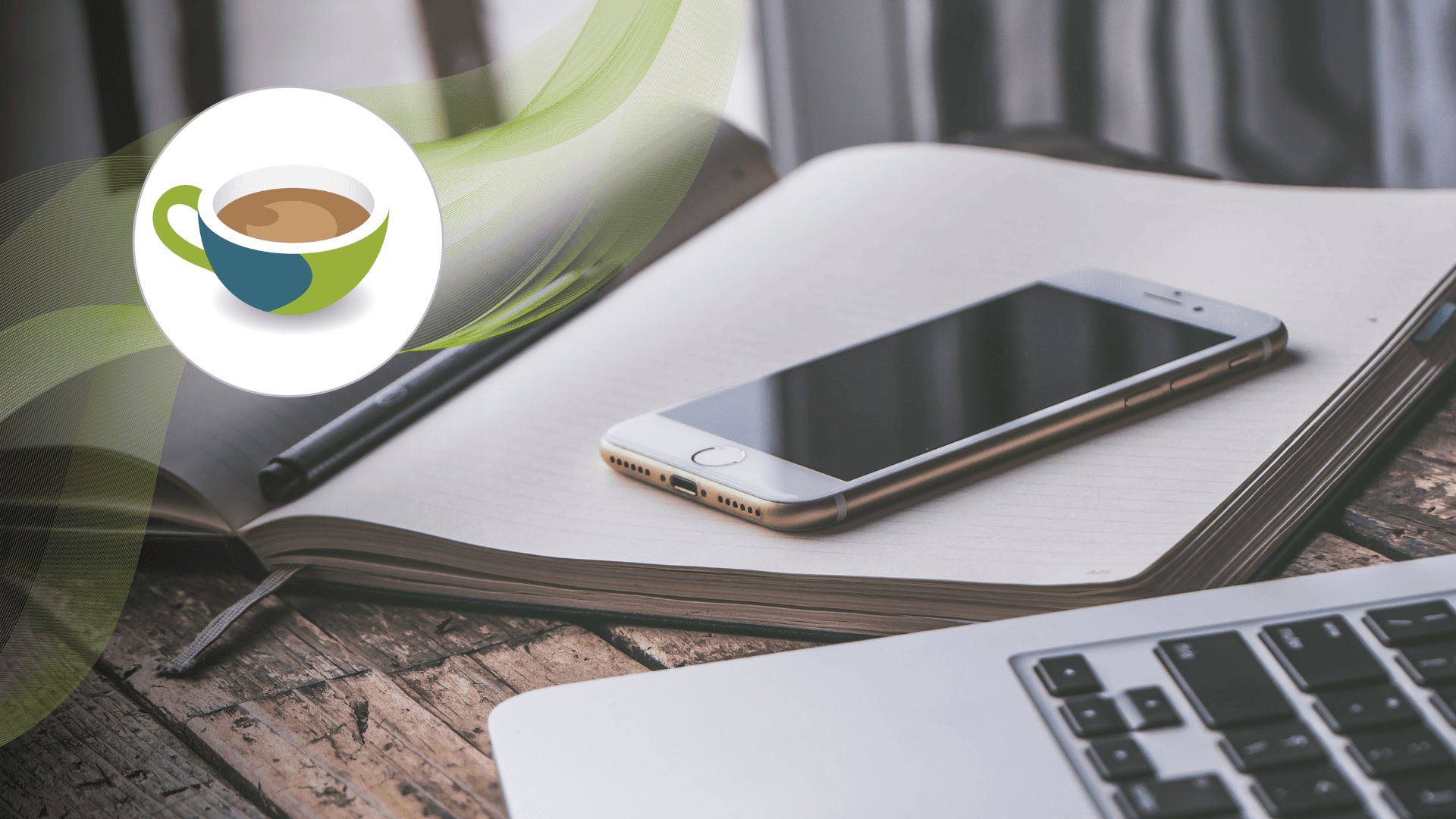 Smartphone resting on an open notebook with a pen beside it, next to a laptop on a wooden desk